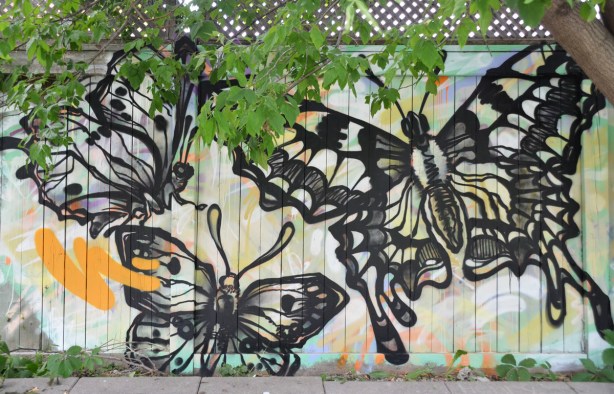Three black line drawings of a butterfly, with details and shadowing, very realistic looking, on a fence