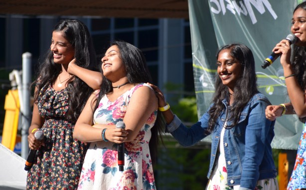 four female singers are smiling, they've just finished a song, performing at Yonge Dundas square as part of Desifest, all 4 are of South Asian descent