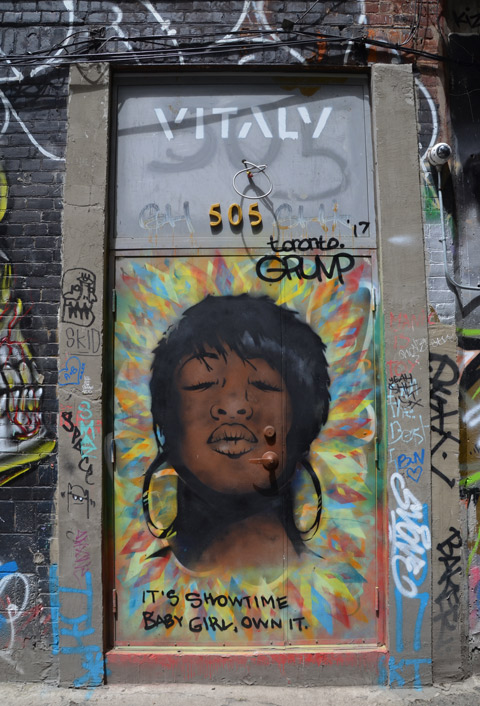 street art painting of a black woman's head, short hair, eyes closed, also on the door is the word vitality and the number 505 