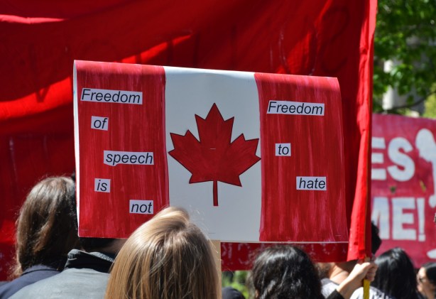 a protest sign in the shape and design of a Canadian flag on the red stripes are words that say Freedom of Speech is not Freedom to hate