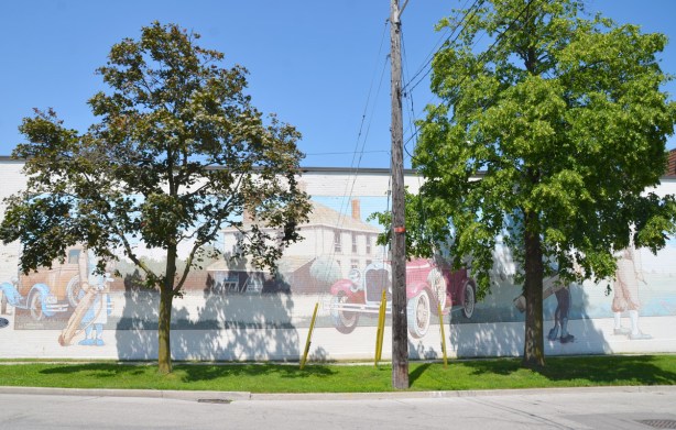 two trees obscure a faded mural 