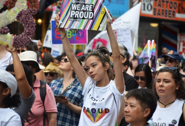 a young woman in the dyke marching is holding up a sign that says Humber, we are proud