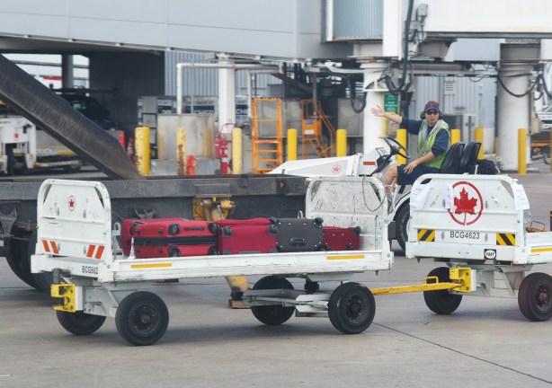 a young man waving, a luggage cart at an airport