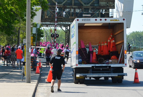 young man is picking up orange traffic cones and putting them into the back of a truck