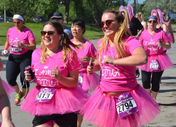 a groupd of women in the Run Like a Diva event, bib number 2794 in pigtails and bib number 2413 running beside her. 