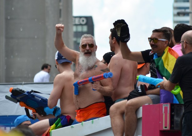 men holding super soakers on top of a pride parade float