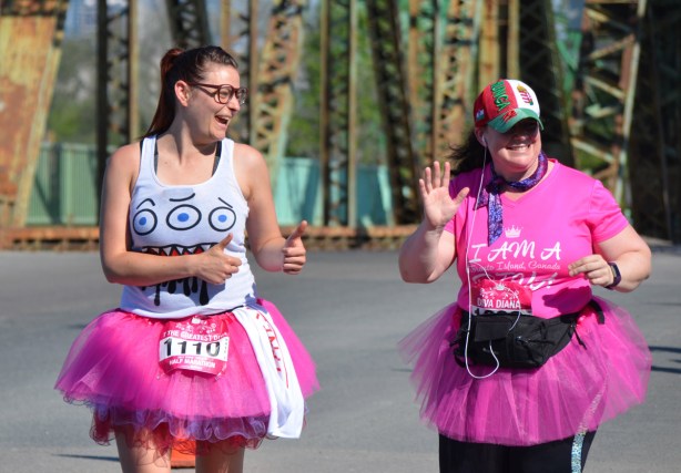 two women wearing pink tutus in the Run Like a Diva half marathon . one of them is the Greatest Diva, bib number 1110