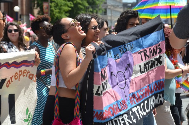 laughing women holding up a banner in support of trans people