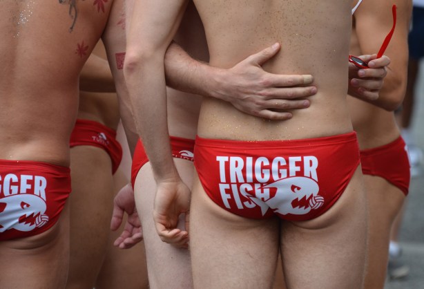 the bums and hands of a few men wearing red swim suits with the words trigger fish on them 