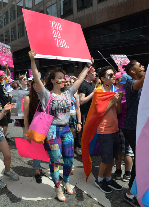 a woman wearing a t shirt that says free hugs is carrying a pink sign that says you do you