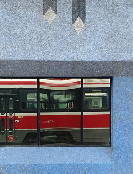 reflections of a TTC streetcar in the window of a pale blue building. 