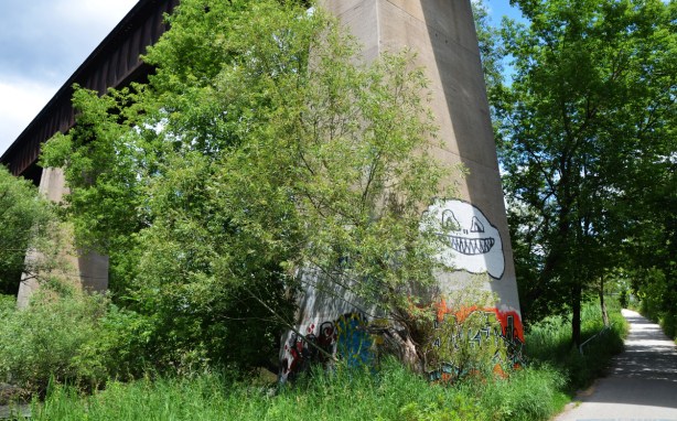 a big white happy face graffiti on a bridge support 