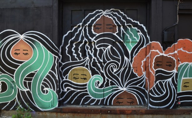 mural, black background with faces with eyes closed and flowing stylized hair 