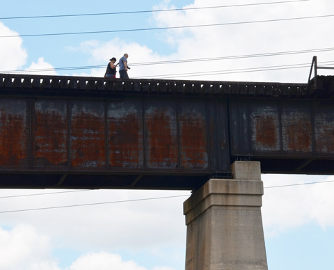 two people walk across an unused railway bridge 