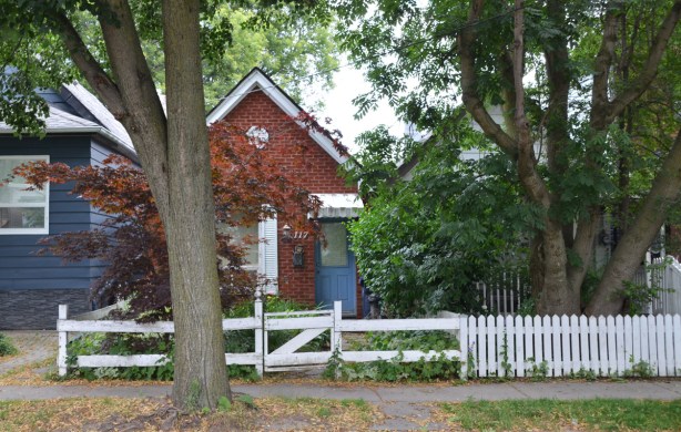 a white fence in front of two small bungalows. On the right it's a picket fence 