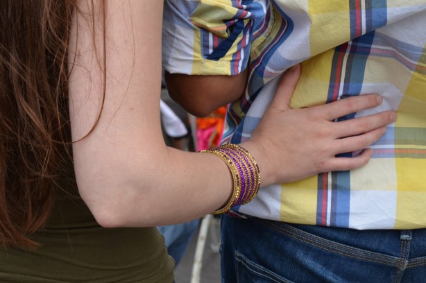 a woman with shiny bangles, bracelets, on her wrist puts her hand on her boyfriend's lower back