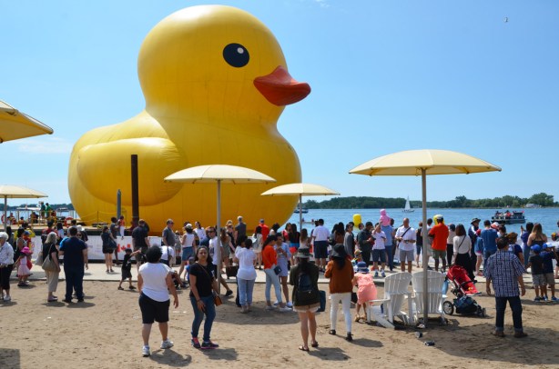 big yellow duck, side view, people on shore
