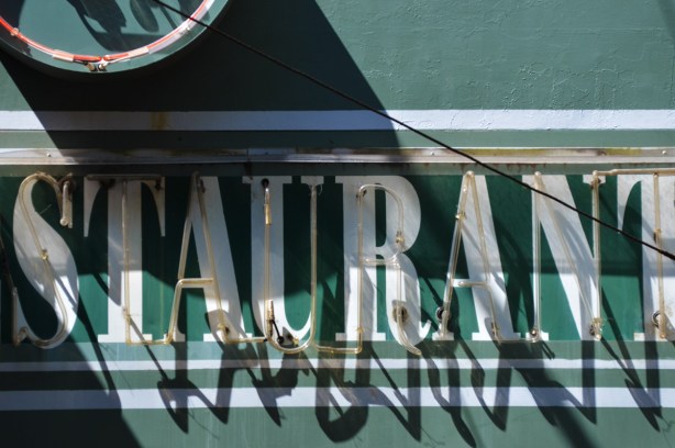 part of a green sign, with white letters that say restaurant. 