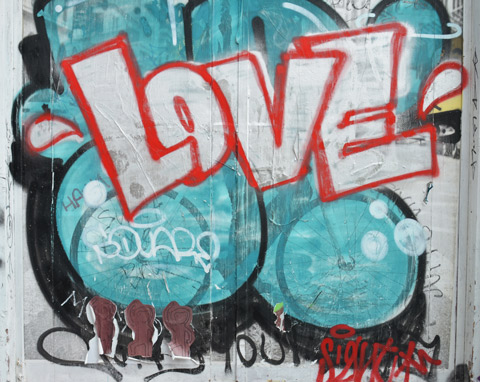the word love in white block letters that are outlined in red, background is turquoise bubbles. below that are three brown pasteups of monkeys