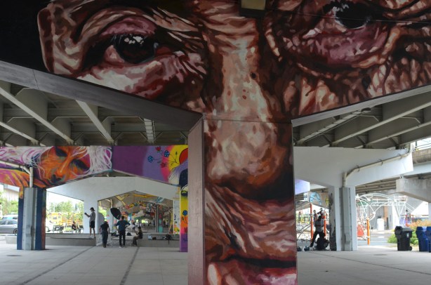 urban open space under a bent that has been painted with a wrinkly brown man's face