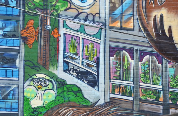 part of Uber 5000 Toronto mural in Graffiti Alley, houses, cat, orange fish, apartments, owl in a tree, 