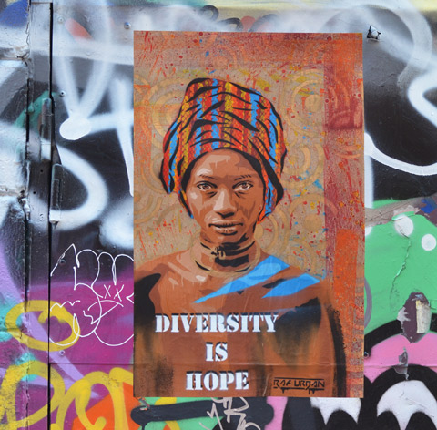 poster street art of a black woman's head and shoulders. She is wearing a head scarf that is striped fabric wound round her head. The words on the poster say Diversity is Hope