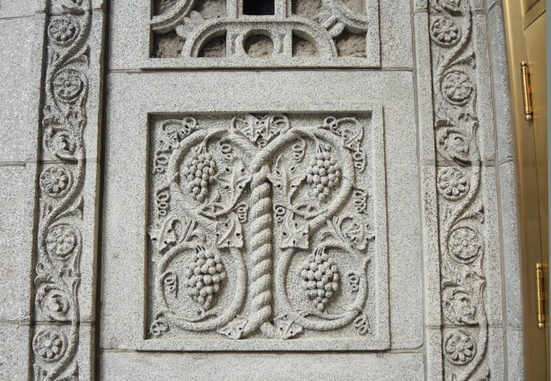 a square panel of stone carved with grapes and grape vines 