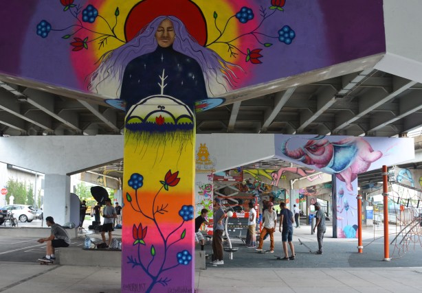 people at Underpass Park, under the expressway, with pillars painted in murals, guys on skateboards,