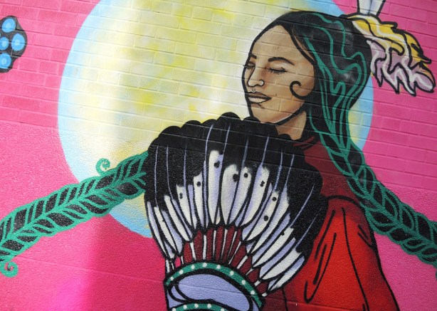 detail of center of mural of an indigenous woman with long braided hair and feathers