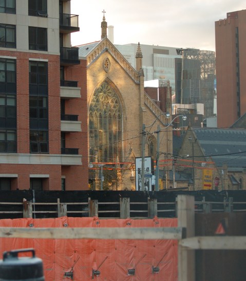 one end of St. Michaels Cathedral with reflected light falling on it, new buildings and construction surround it 