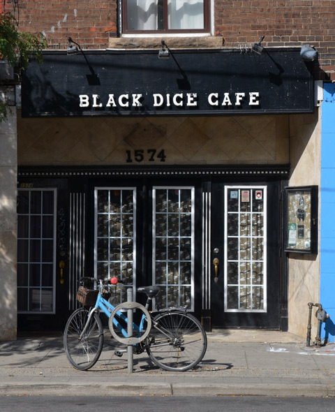 a blue bike is parked outside the glass windows and door of the black dice cafe 