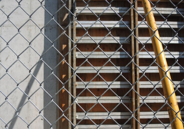 chainlink fence in front of rows of construction equipment