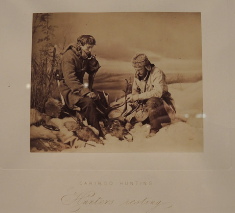 vintage photo of two men hunting caribou. Resting with their rifles. 