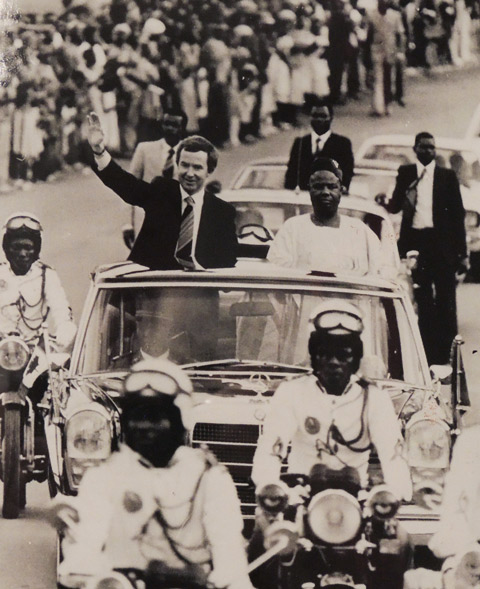 black and white photo from 1979 of Joe Clark, then Prime Minister of Canada, riding in a motorcade with the President of Cameroon, in Cameroon. 
