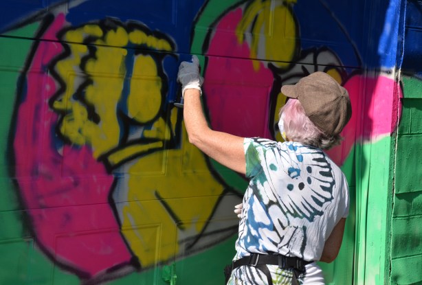 a woman is painting a street art mural