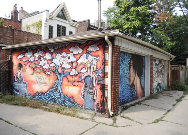 a two car garage in an alley, murals on both garage doors as well as on the side of the building