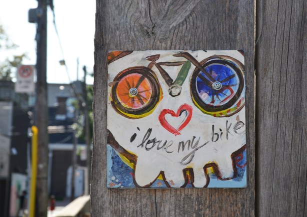 a little painting of a bike and a heart that makes it look like the wheels are eyes and the heart is a mouth