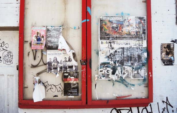 old glass case for posters, red frame around the glass, posters stuck on the front of the glass