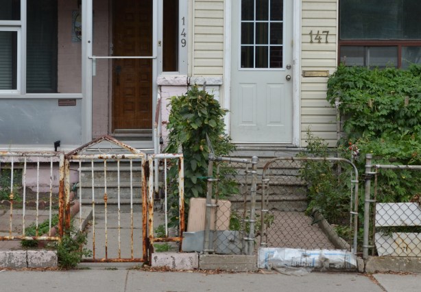 a fence across the front of two houses, each with their own sidewalk and gate. 