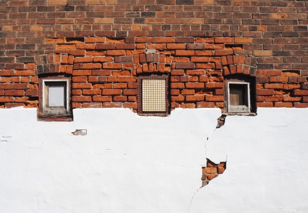 three small windows in a wall, the top part of the wall is brick and the bottom is plaster that has been painted white 
