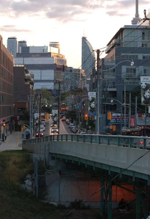 looking along King street from beside ramp over the railway tracks - light under the bridge shows someone sitting there, city scene in the rest of the photo 