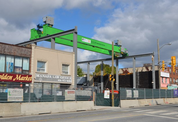 a large horizontal crane stretches over a vacant lot where a subway station is being built 