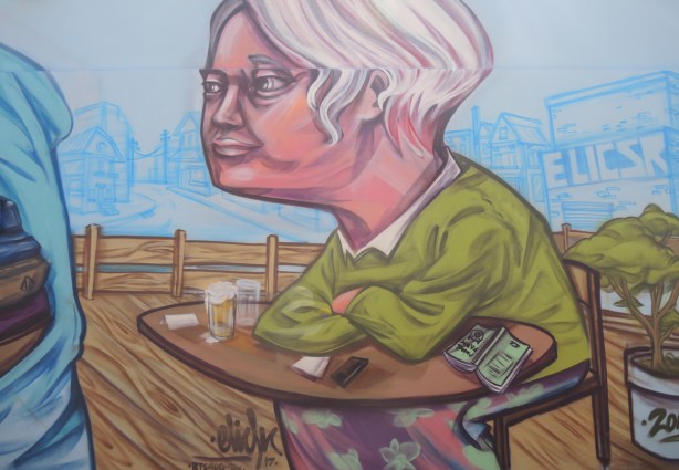 finished section of a mural, with man with grey hair sitting with elbows on a table, 