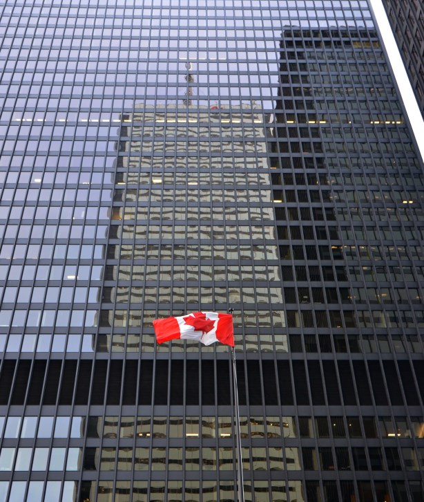 reflections in the black Commerce Court buildings, with a Canadian flag flying in front of the building. 