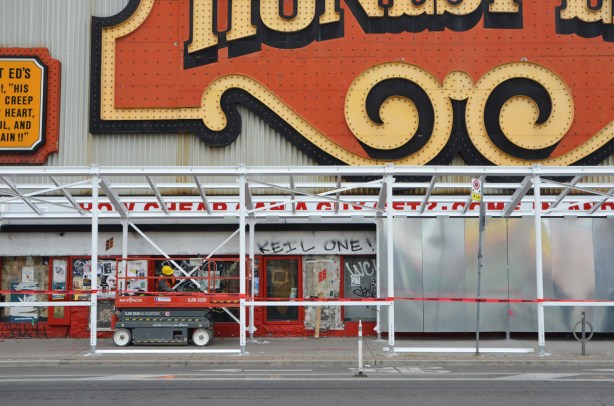 the start of grey hoardings going up around the old Honest Eds store on Bloor Street as preparations are made to demolish it