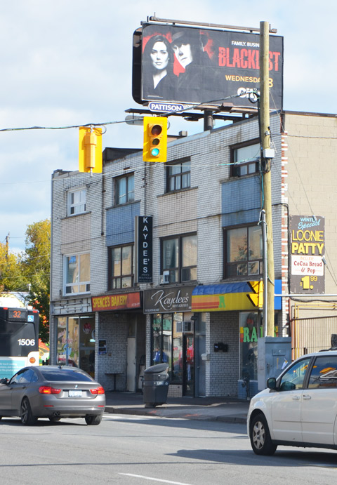three storey brick building with stores on the ground level, traffic in front, 