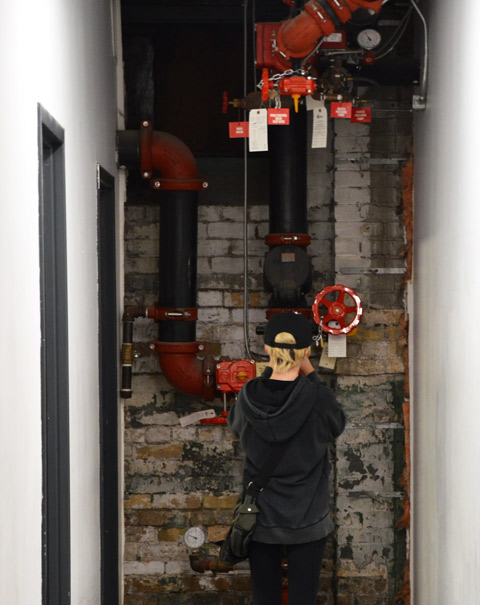 the back of a person takeing a close up picture of a dial or part of a pipe system