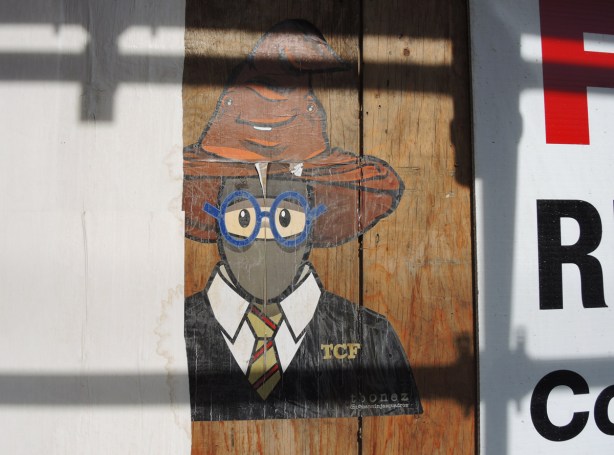 a large tbonez pasteup of an urban ninja squadron character, head and shoulders, but wearing a shirt and tie and blue rimmed glasses, also a brown pooh hat on his head. 