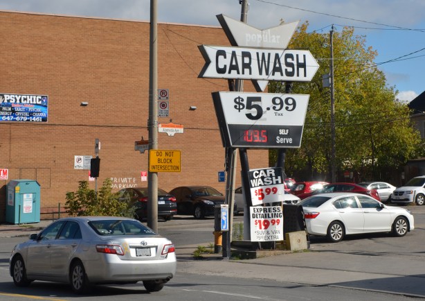 an old sign for popular car wah, $5.99 in front of a gas station 