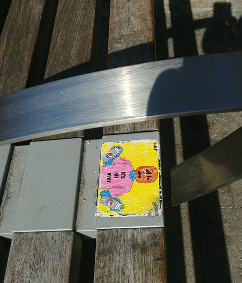 sticker on a bench, it's all over, with pumpkin head 